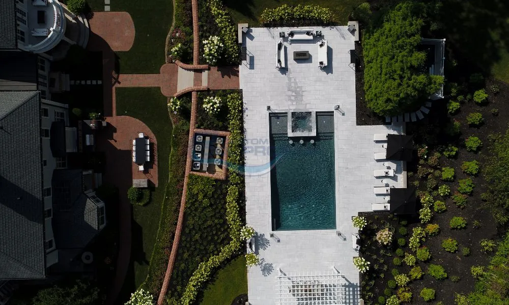 Aerial view of a luxurious backyard featuring a modern swimming pool surrounded by elegant lounge chairs, a stylish patio area, and meticulously landscaped gardens, showcasing a perfect outdoor retreat for relaxation and entertainment, backyard pool