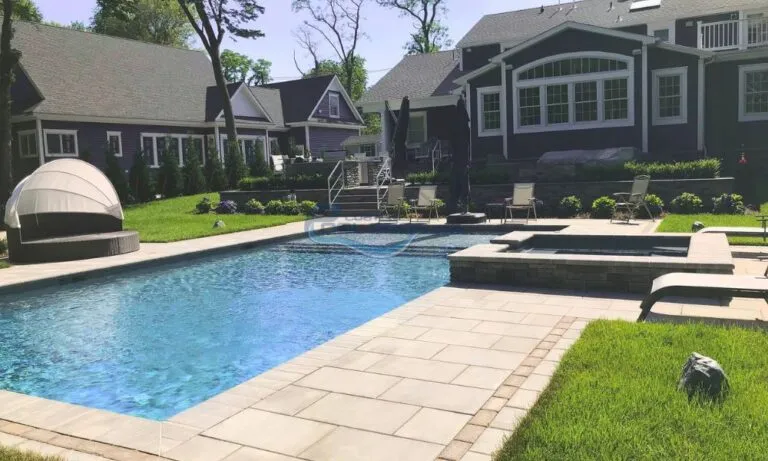 Beautiful backyard oasis featuring a sparkling blue swimming pool, surrounded by lush green grass and vibrant landscaping. The area includes a modern hot tub and comfortable lounge chairs, with stylish outdoor furniture and a cozy cabana for relaxation. The elegant home in the background showcases large windows and a contemporary design, making this space perfect for outdoor entertaining and leisure activities, Swimming pool companies in New Jersey